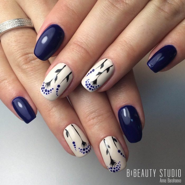 Uñas pintadas de azul y blanco con diseño de flores y puntos