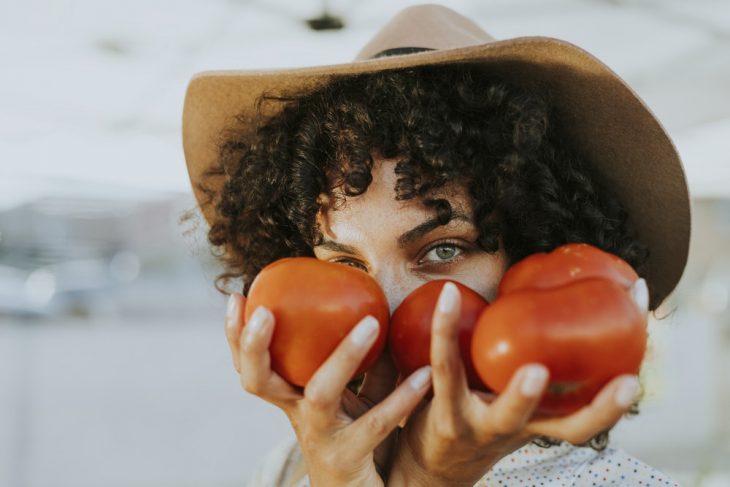 chica sosteniendo tomates en sus manos