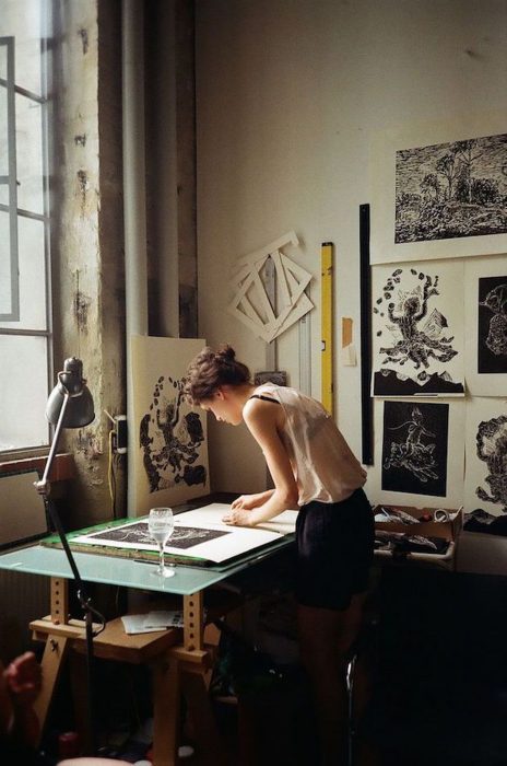 Chica dibujando en escritorio con una copa de agua