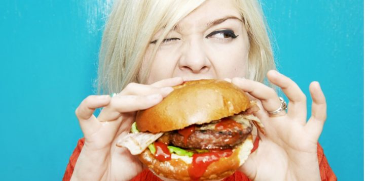 mujer rubia comiendo una hamburguesa 