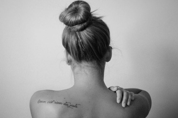 espalda de mujer con tatuaje frase frances