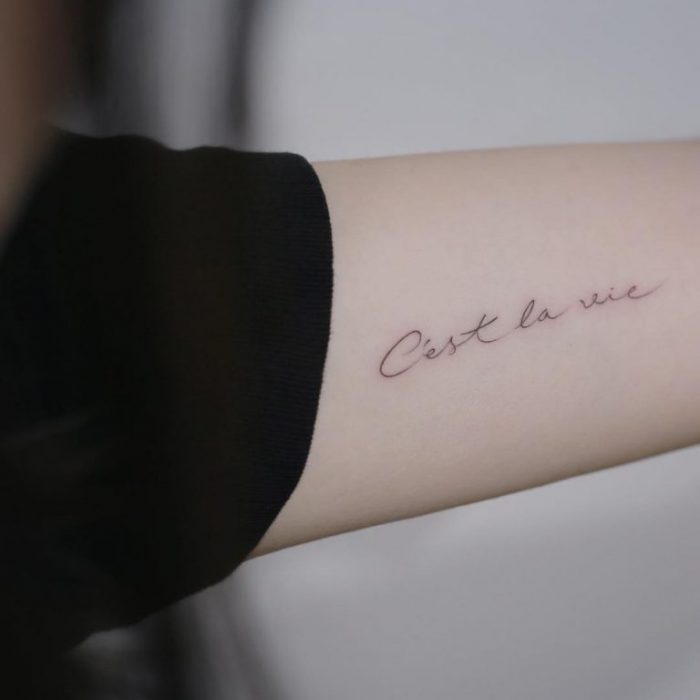 mujer con tatuaje de frase en el brazo