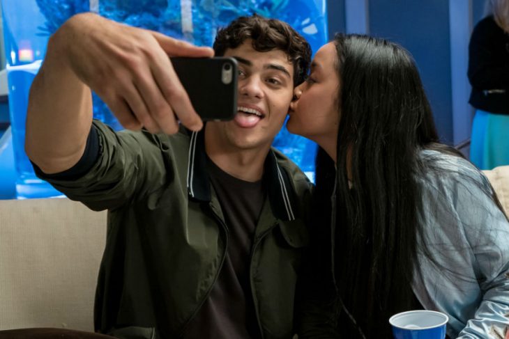 hombre con celular tomando selfie y mujer besandolo