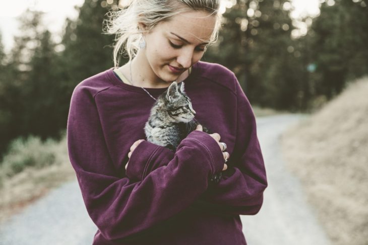 chica cargando un gato pequeño 