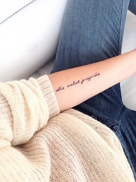 mujer con tatuaje de frase en el brazo