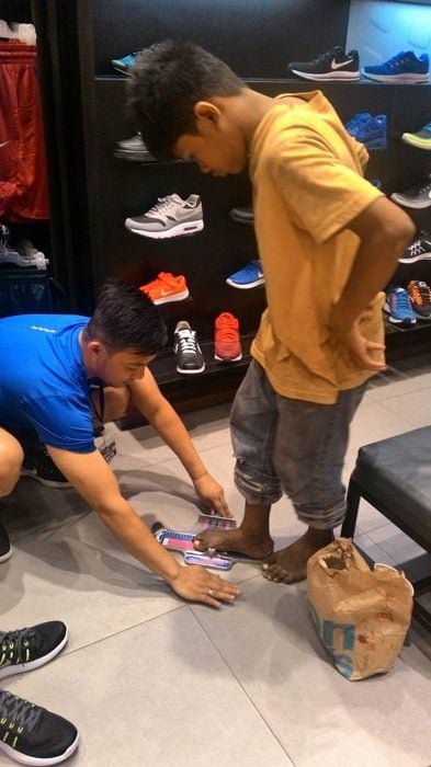 Hombre midiendo los pies de un niño de la calle descalzo