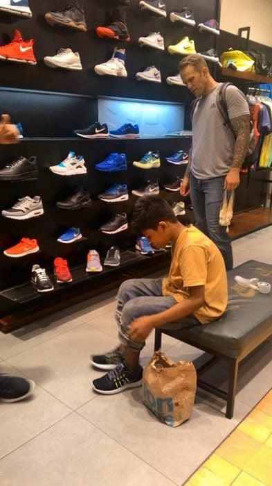 Niño de la calle midiéndose zapatos que un turista le regaló