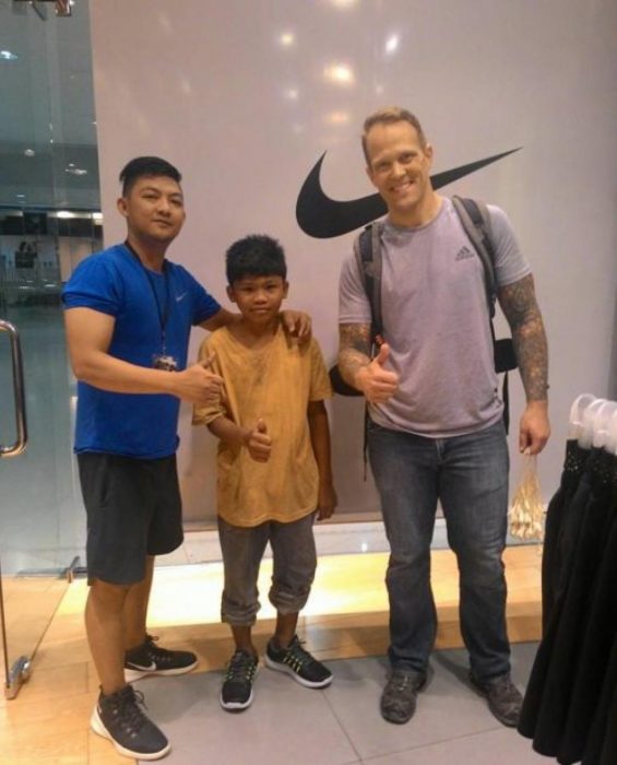 Niño de la calle junto a turista y empleado de una tienda de zapatos