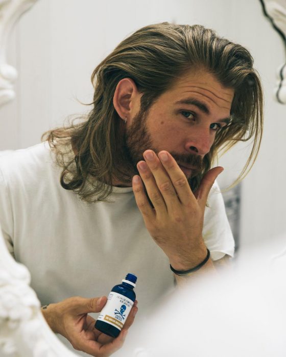 Hombre de cabello rubio y largo con barba, frente al espejo