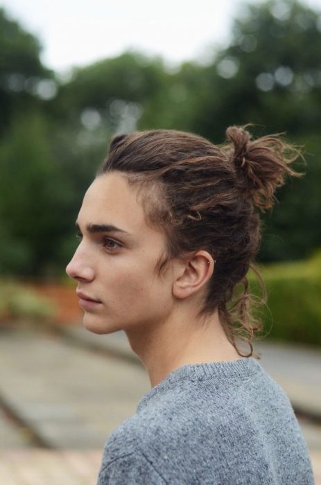 Hombre de perfil con cabello largo agarrado en un chongo