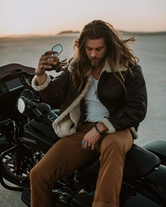 Hombre de cabello largo y barba encima de una motocicleta