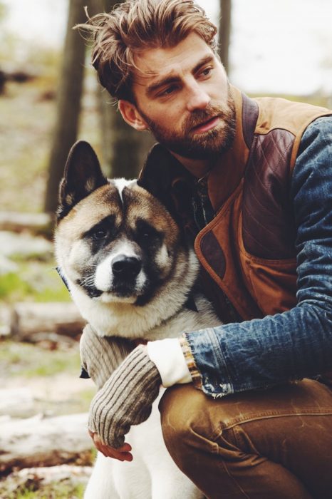 Hombre rubio con barba abrazando a un perro