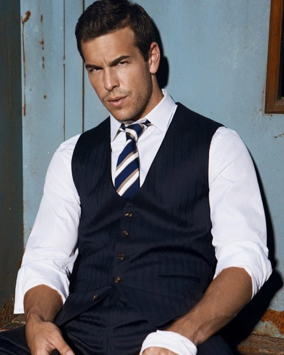 Hombre con camisa blanca, corbata y chaleco azul