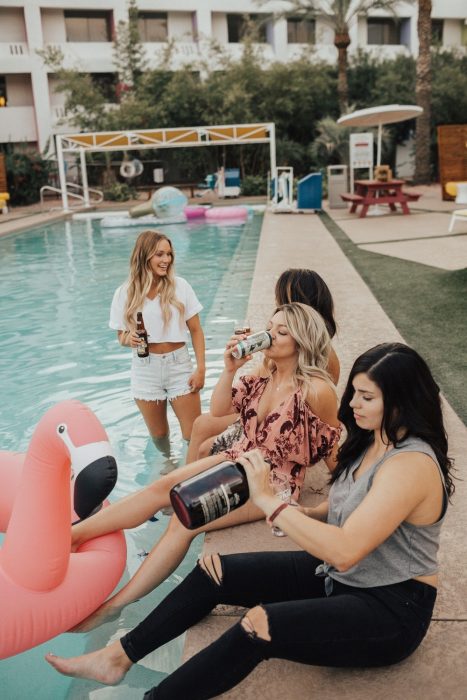 amigas bebiendp cerveza alrededor de la piscina 