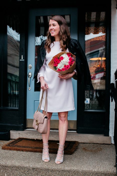 Mujer con vestido blanco y chaqueta de cuero con ramo de flores