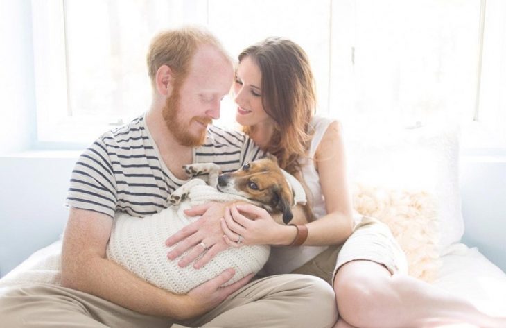 pareja cargando a un perro como si fuera un bebé 