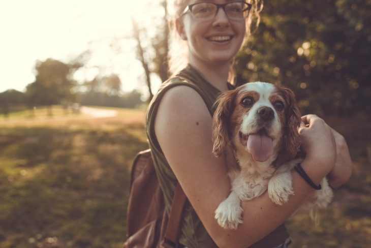 chica cargando a su perro 