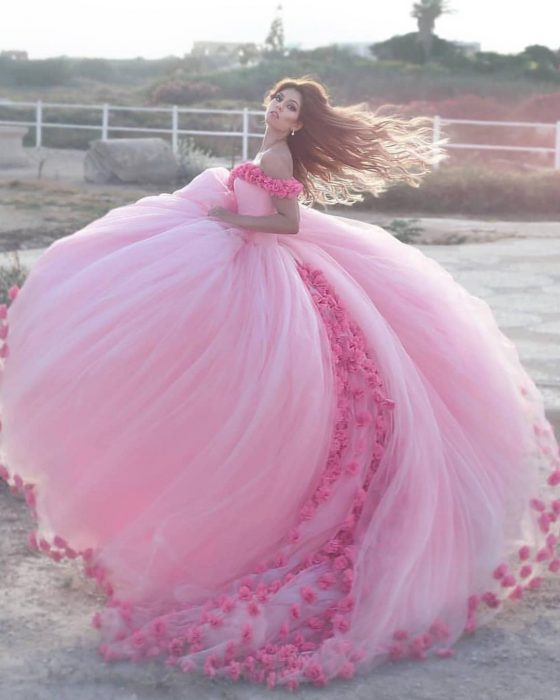 Chica con vestido para XV años de corte princesa color rosa con flores y tul