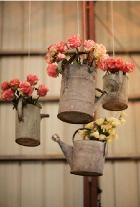 Regaderas de agua con flores dentro colgadas 