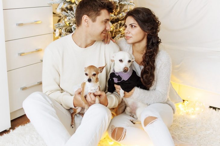 pareja cargando a un perro entre sus brazos