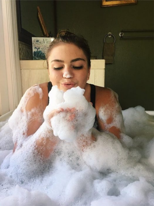 mujer en tina de baño con espuma 