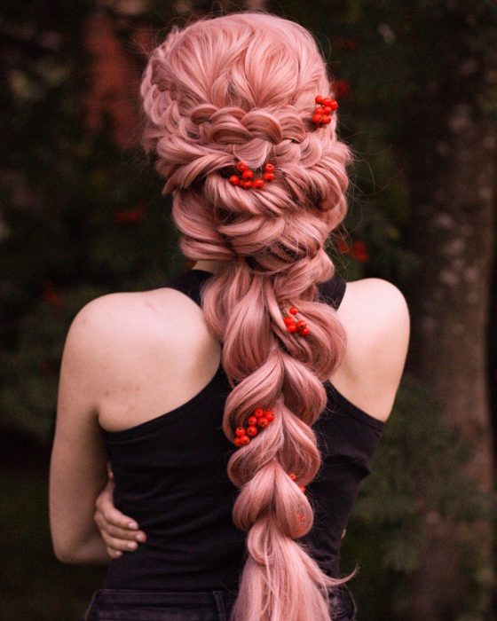 Chica de cabello rosa con trenza adornada con flores