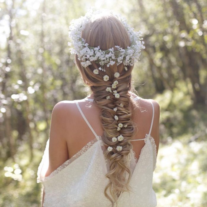 Chica rubia con trenza de espiga adornada con corona de flores blancas