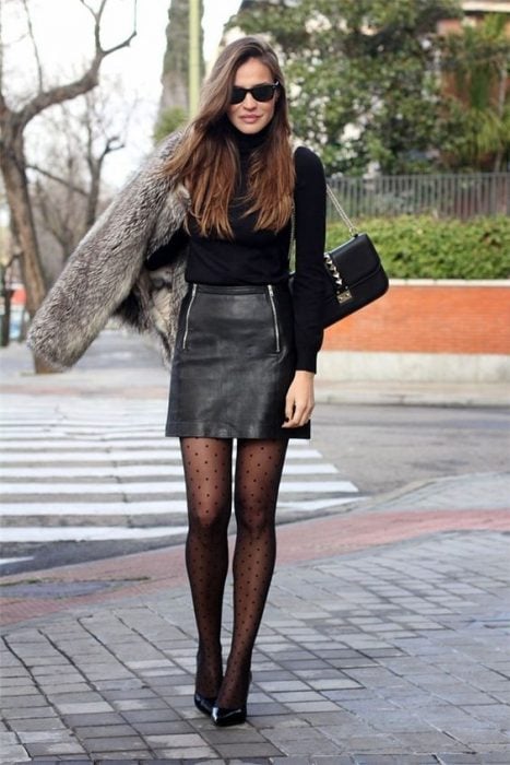  Chica por la calle con falda de piel, suéter negro y stilettos 