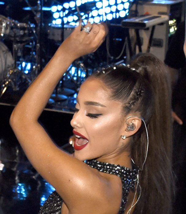 Ariana Grande con el brazo levantado mientras canta y muestra su anillo de compromiso 