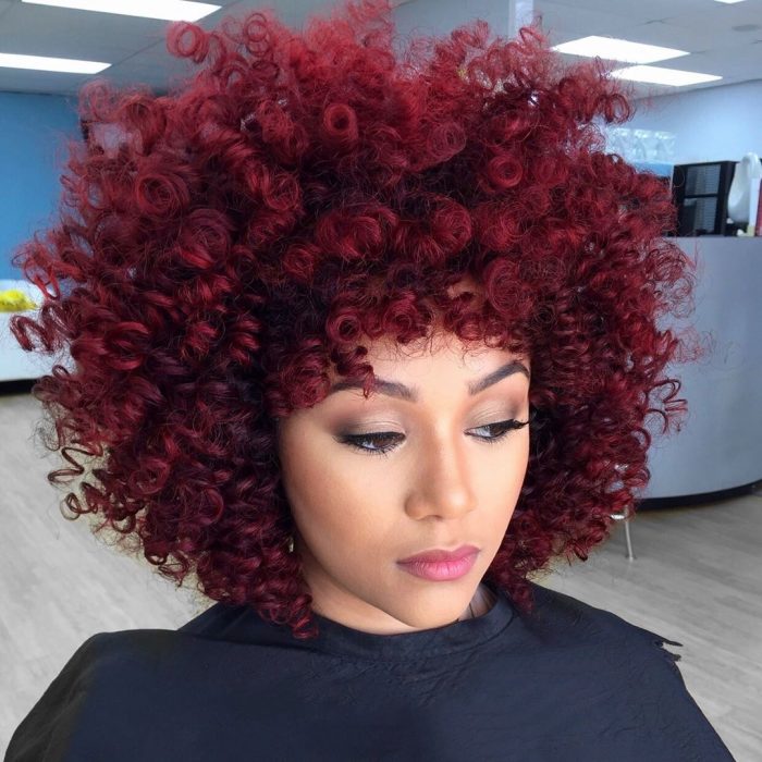 Chica con cabello rojo borgoña chino tipo afro