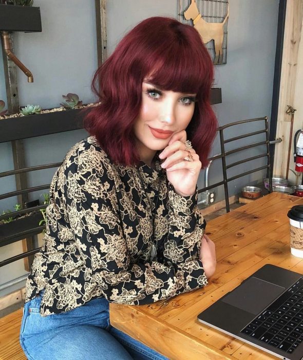 Chica con cabello rojo borgoña sentada en un restaurante