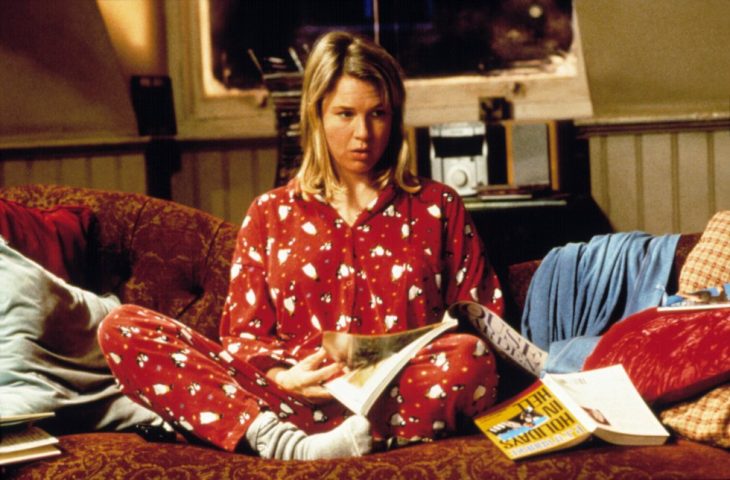 Escena de chica en pijama sentada en un sillón leyendo una revista de la película el diario de Bridget Jones 