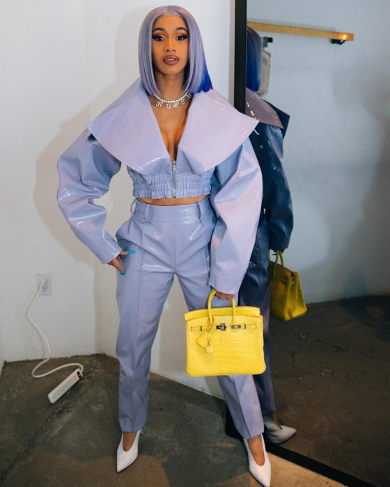 Cardi B usando un traje morado con una bolsa de color amarillo meintras posa para una foto de Instagram