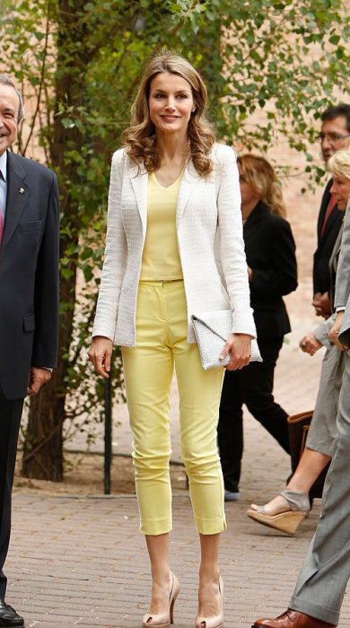 Reina Letizia Ortiz caminando por las caslles mientras usa un atuendo amarillo y un blazer de color hueso 