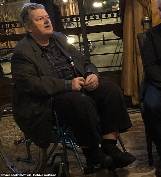 El actor Robbie Coltrane sentado en una silla de ruedas para promover un juego en universal studios