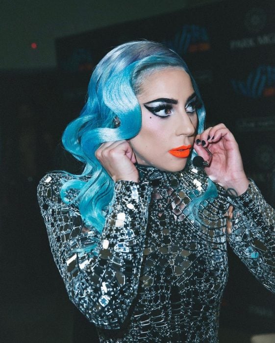 Lady Gaga con cabello ondulado de color azul cielo, delineado cat eye pronunciado y vestido de espejos