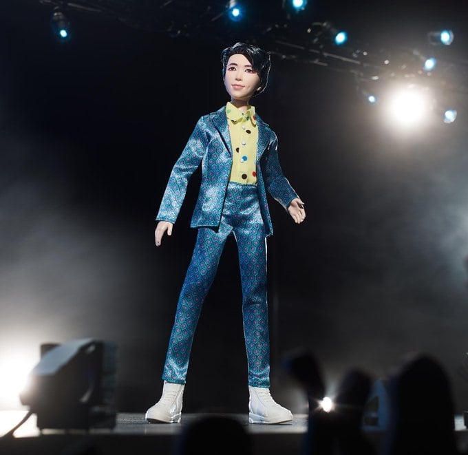 Muñeco inspirado en el cantante de la banda de K-pop, BTS, RM usando un traje de color azul metalico con tenis blancos y camisa de color amarillo 