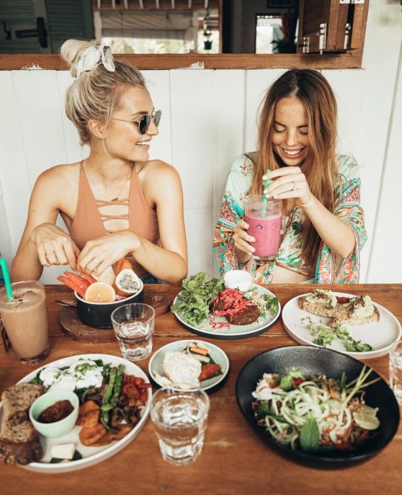 Mejores amigas sonriendo y comiendo en restaurante