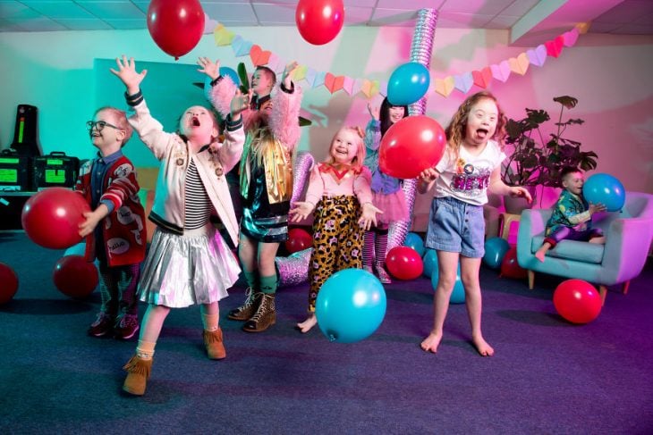 Niños con síndrome de Down jugando con globos de color azul y rojo dentro de una sala de espera