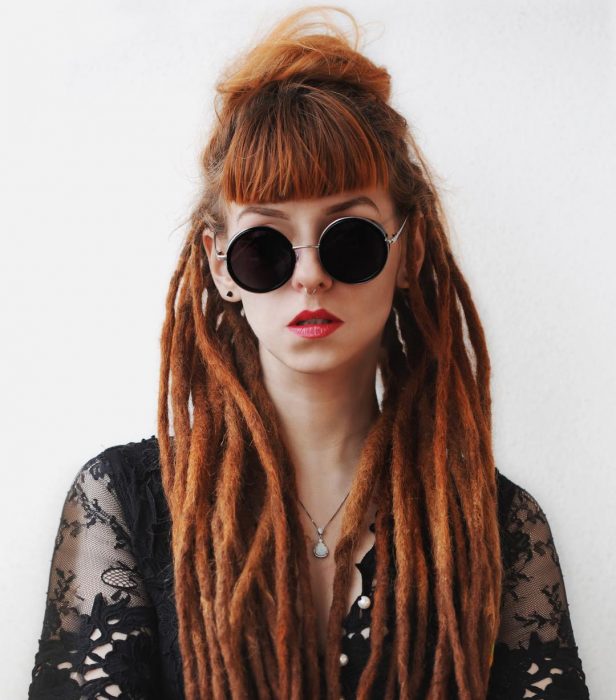 Chica pelirroja con rastas y lentes redondos de sol