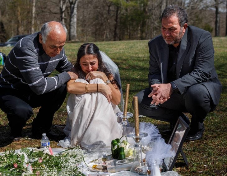 Mujer con su vestido de novia llorando en la tumba de su prometido