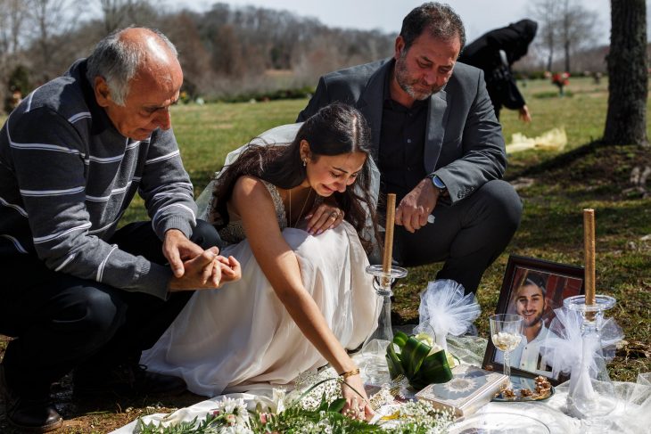 Mujer con su vestido de novia llorando en la tumba de su prometido