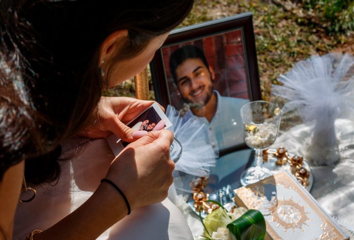 Mujer con su vestido de novia llorando en la tumba de su prometido