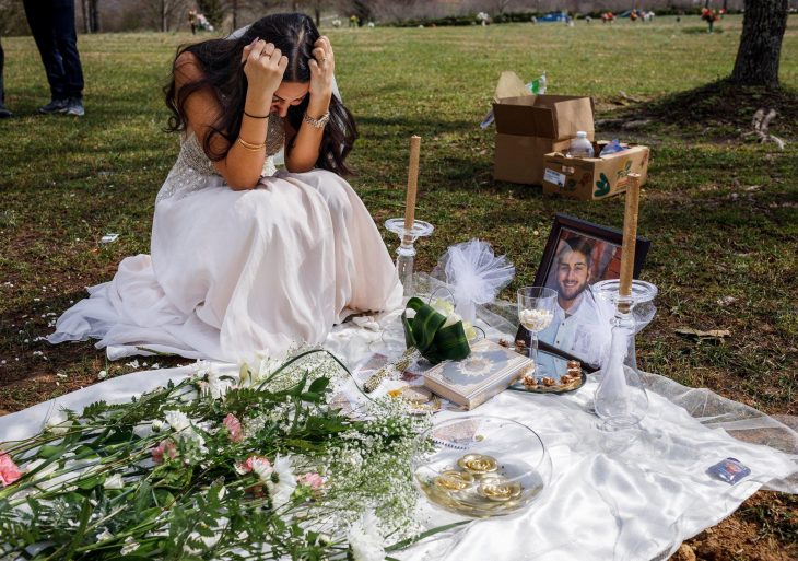 Mujer con su vestido de novia llorando en la tumba de su prometido