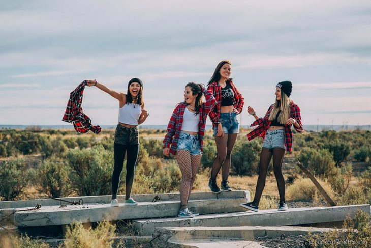 Cuatro mujeres en la naturaleza con shorts y camisas de cuadros rojos que combinan