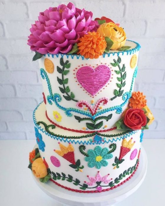 Pastel mediano decorado con betún en efecto bordado con corazones, flores y estrellas