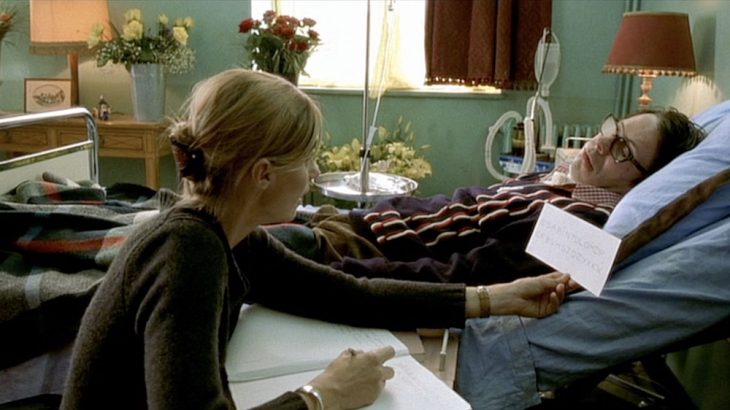 escena de la película El llanto de la mariposa - hombre parapléjico en cama con mujer que escribe
