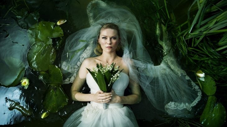 Kristen Dust para la película de Melancolía vestida de novia flotando sobre agua rodeada de plantas