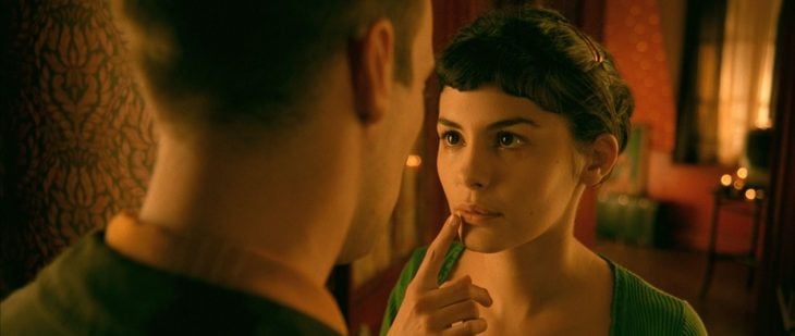 Audrey Tautou en Amélie - chica con cabello negro recogido tocándose la boca