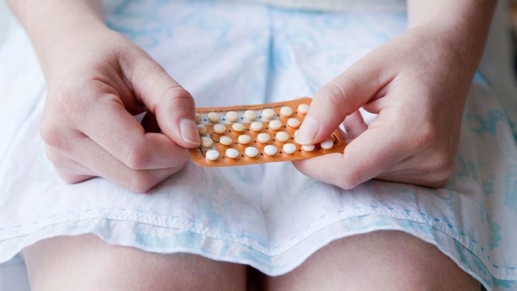 Chica sujetando en las manos una cartera de pastillas anticonceptivas